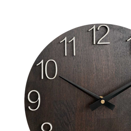 Drewniany zegar ścienny z rzeźbionymi cyframi i metalowymi wskazówkami.