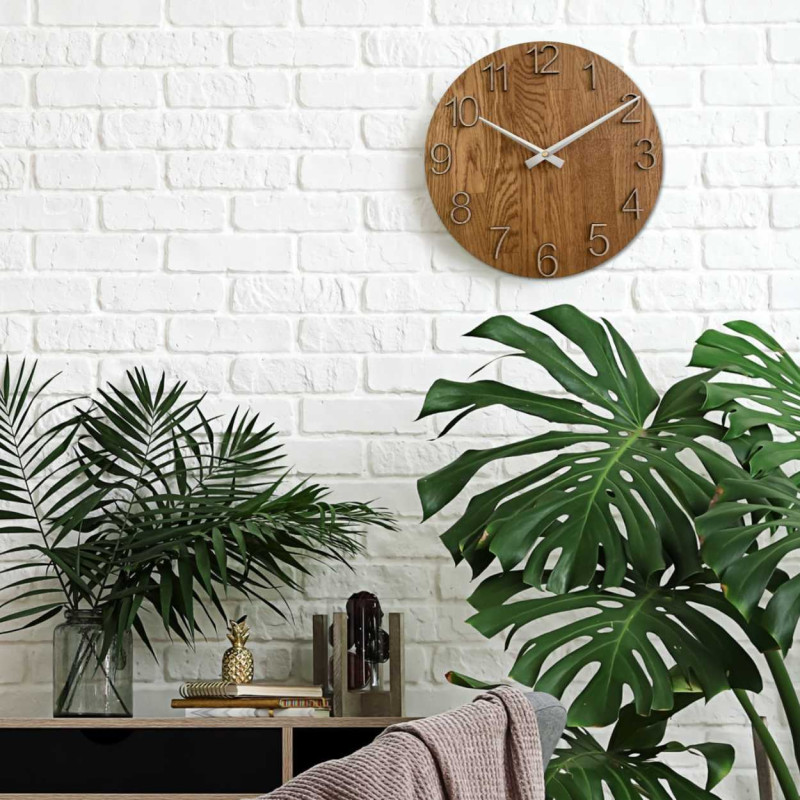 Okrągły zegar z ozdobnym wycięciem w środku i delikatnym wzorem drewna.