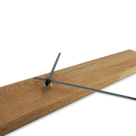 Minimalistyczny drewniany zegar w kształcie wąskiego panelu ze srebrnymi i czarnymi wskazówkami.