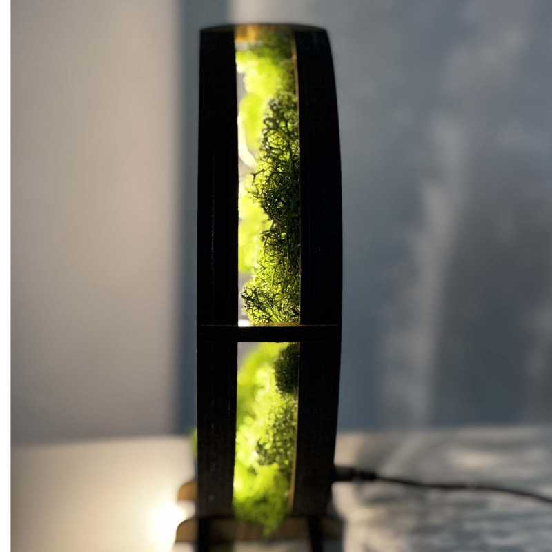 Zbliżenie na podświetlone, drewniane Drzewo Życia otoczone mchem.