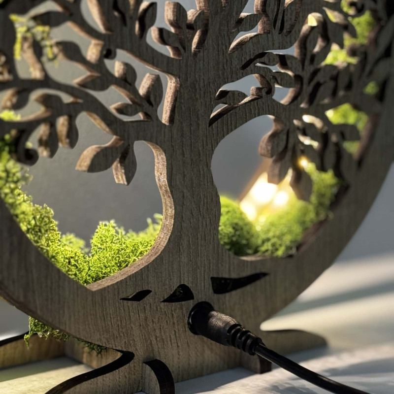 Zbliżenie na podświetlone, drewniane Drzewo Życia otoczone mchem.